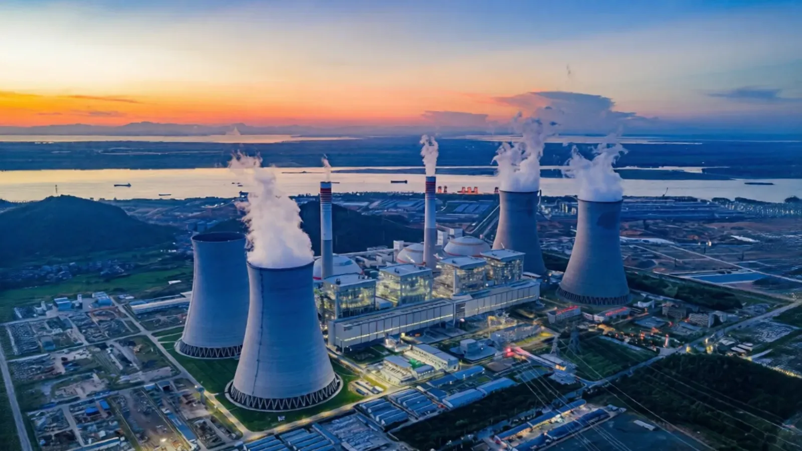 Aerial view of a power station with cooling towers at dusk